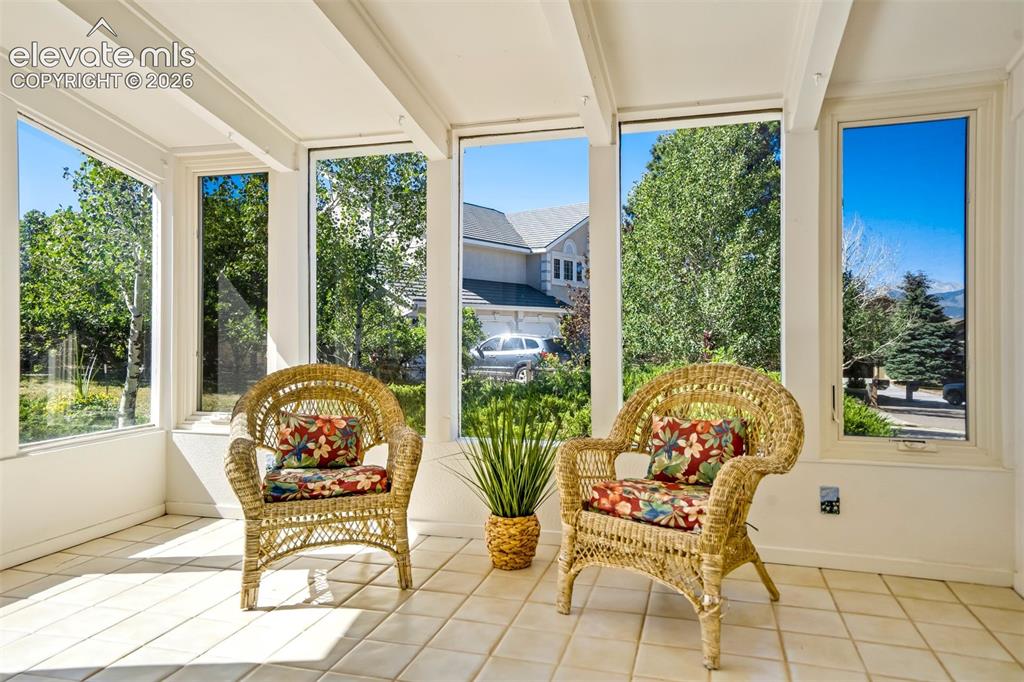Image 5 of 45: Sunroom featuring white-painted exposed beam ceiling, large windows with wh