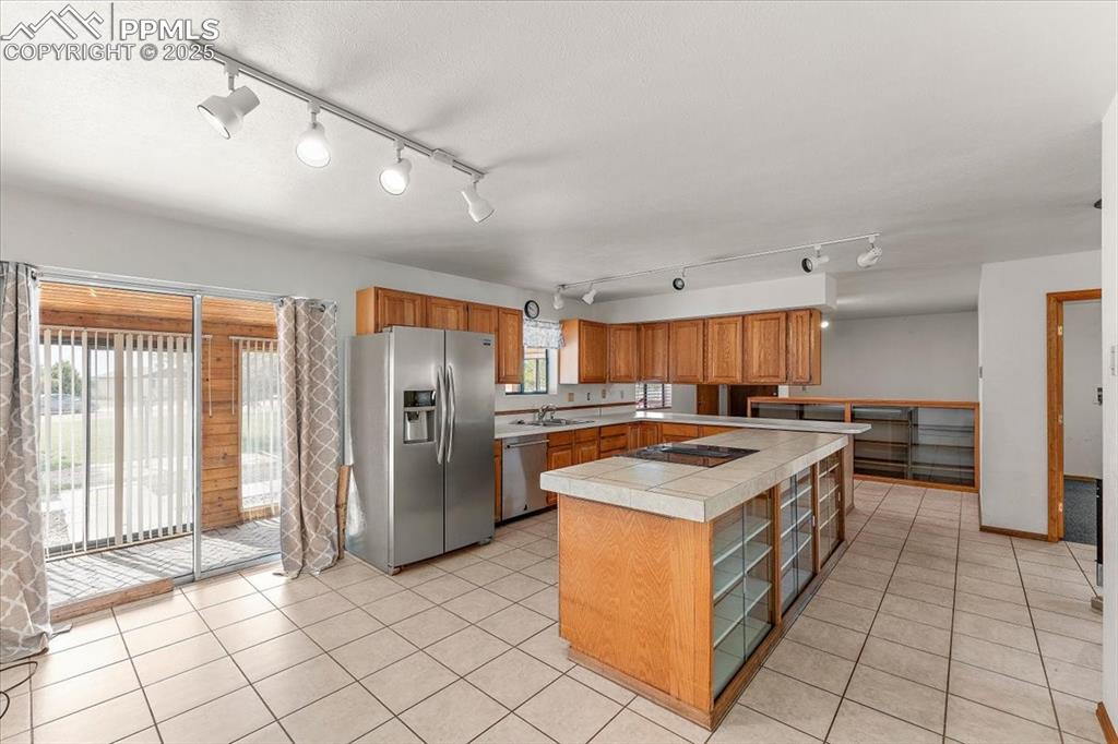 Image 13 of 44: Kitchen with appliances with stainless steel finishes, rail lighting, brown