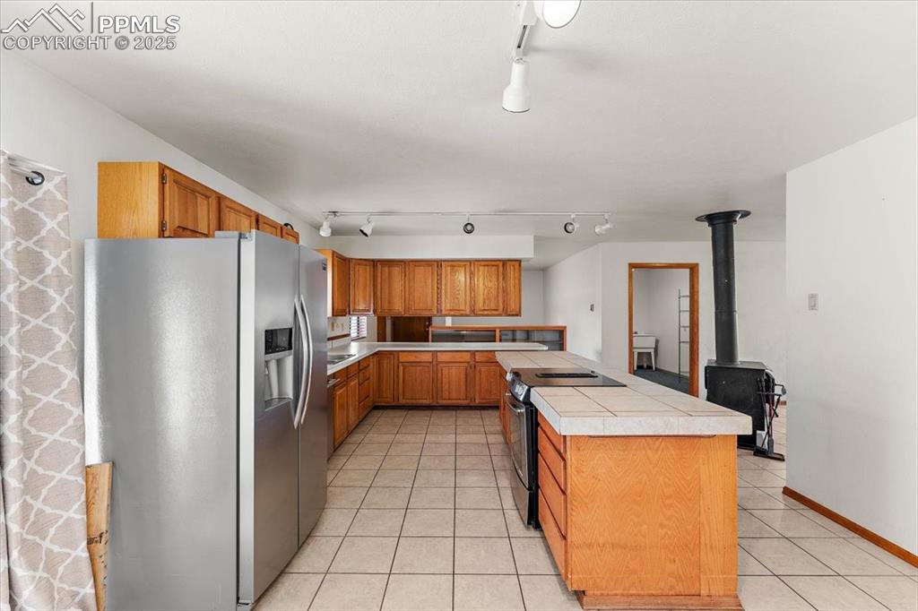 Image 14 of 44: Kitchen featuring stainless steel fridge with ice dispenser, brown cabinets