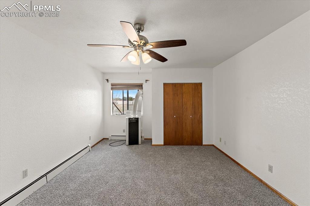 Image 19 of 44: Unfurnished bedroom featuring baseboard heating, carpet floors, a closet, c