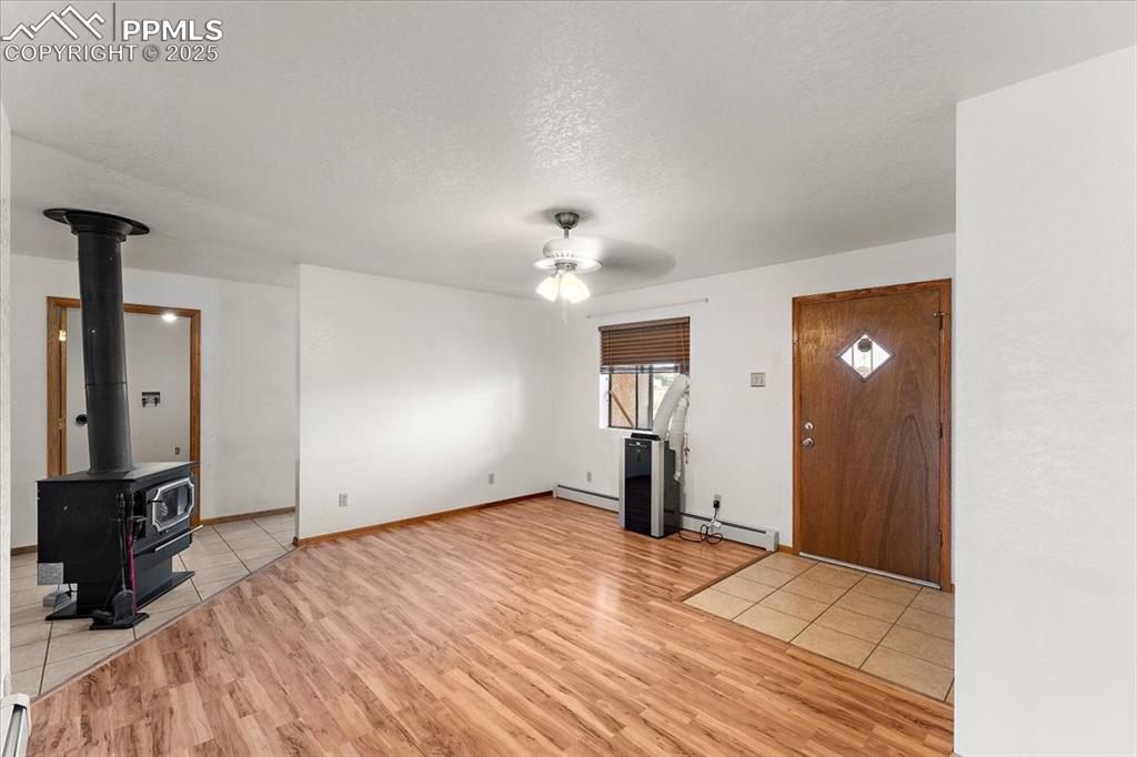 Image 2 of 44: Unfurnished living room featuring a wood stove, a textured ceiling, light w