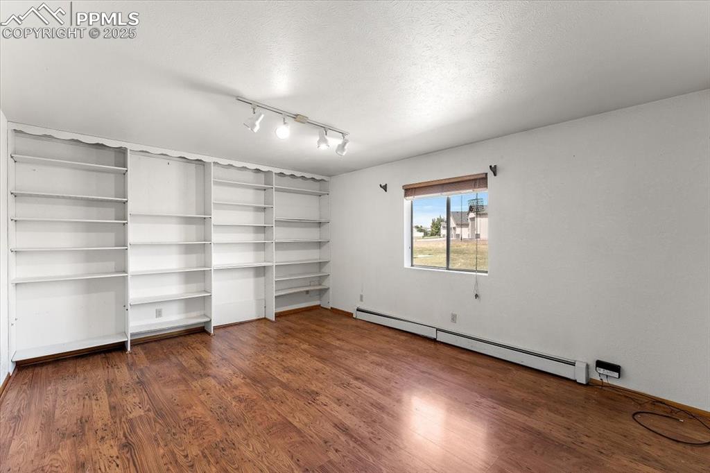 Image 25 of 44: Unfurnished room featuring a baseboard heating unit, dark wood-style floori