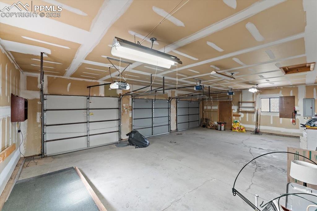 Image 34 of 44: Garage with electric panel and a garage door opener