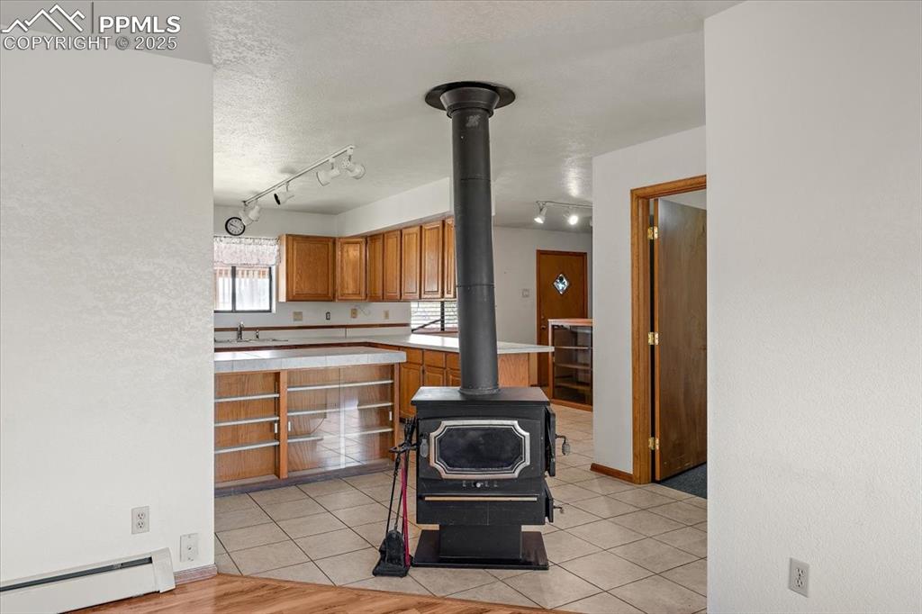 Image 4 of 44: Kitchen featuring brown cabinetry, light tile patterned floors, a baseboard
