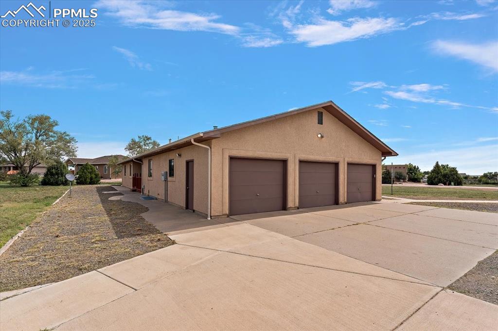 Image 40 of 44: View of side of property with a garage, stucco siding, and concrete drivewa