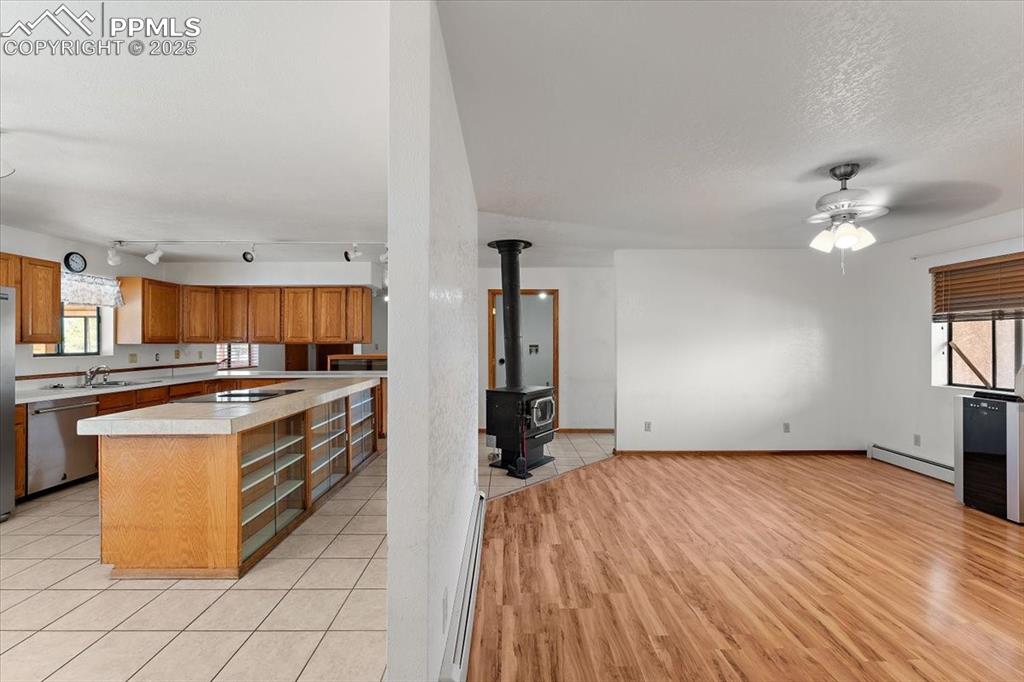Image 6 of 44: Kitchen with light countertops, brown cabinets, dishwasher, a center island