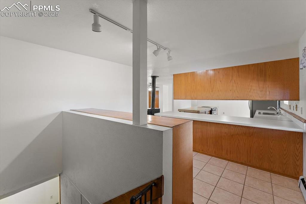 Image 8 of 44: Kitchen with track lighting, light tile patterned flooring, a peninsula, li