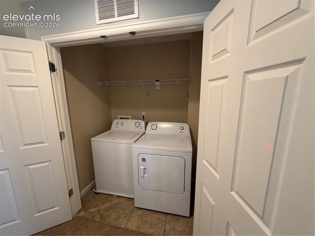 Image 19 of 26: Dedicated laundry closet with white appliances and wire shelving
