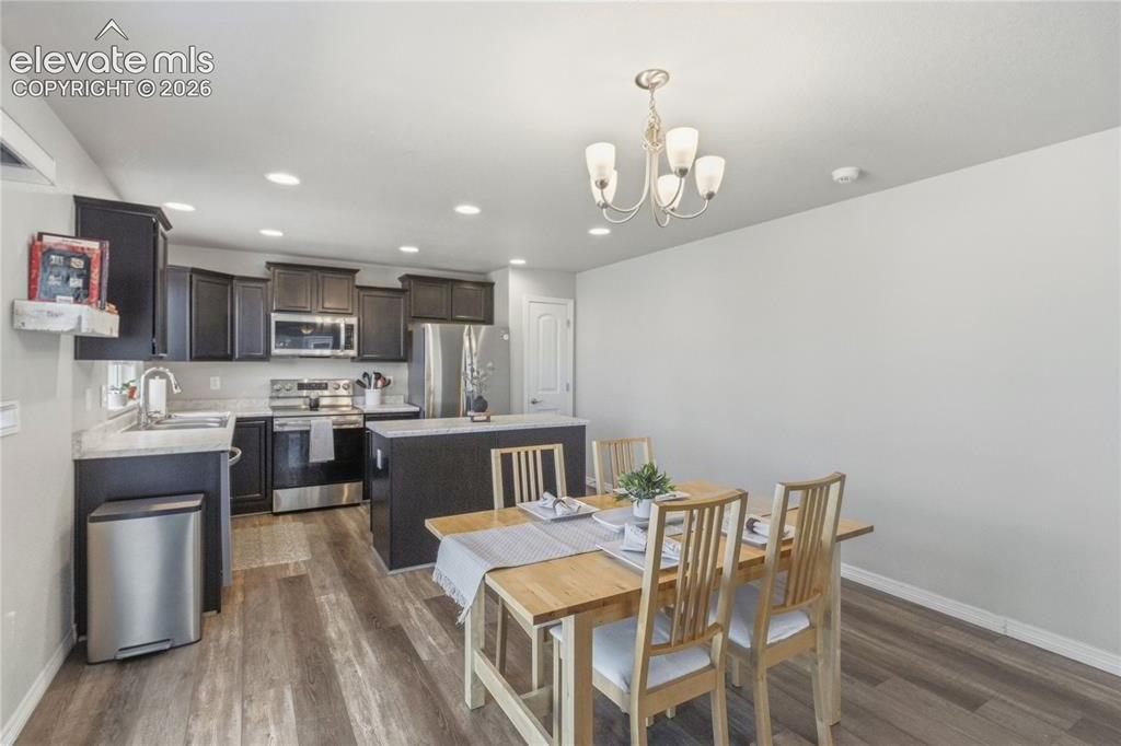 Image 12 of 50: Modern kitchen and dining area with LVP flooring, wood cabinetry, stainless