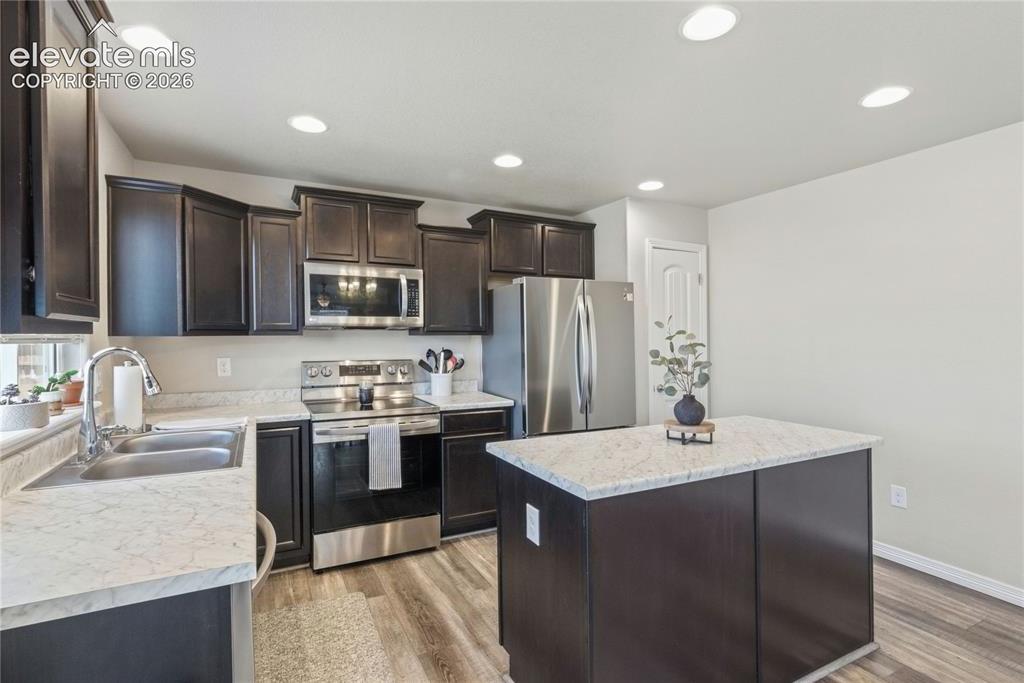 Image 13 of 50: Modern kitchen featuring wood cabinetry, light-colored countertops, stainl