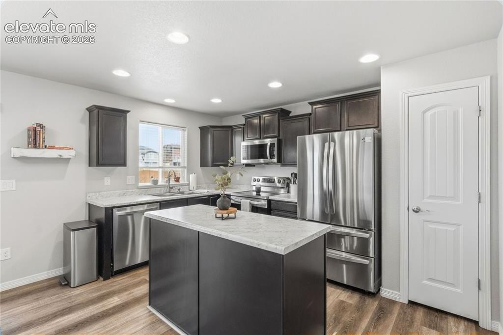 Image 14 of 50: Kitchen featuring wood cabinetry, stainless steel appliances, a center isla