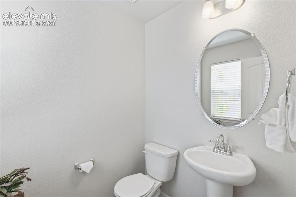 Image 15 of 50: 1/2 Bath on main level Pedestal sink with chrome faucet, oval mirror, and w