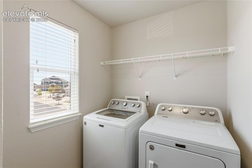 Image 25 of 50: Dedicated laundry area featuring a window with blinds, upper wire shelving,