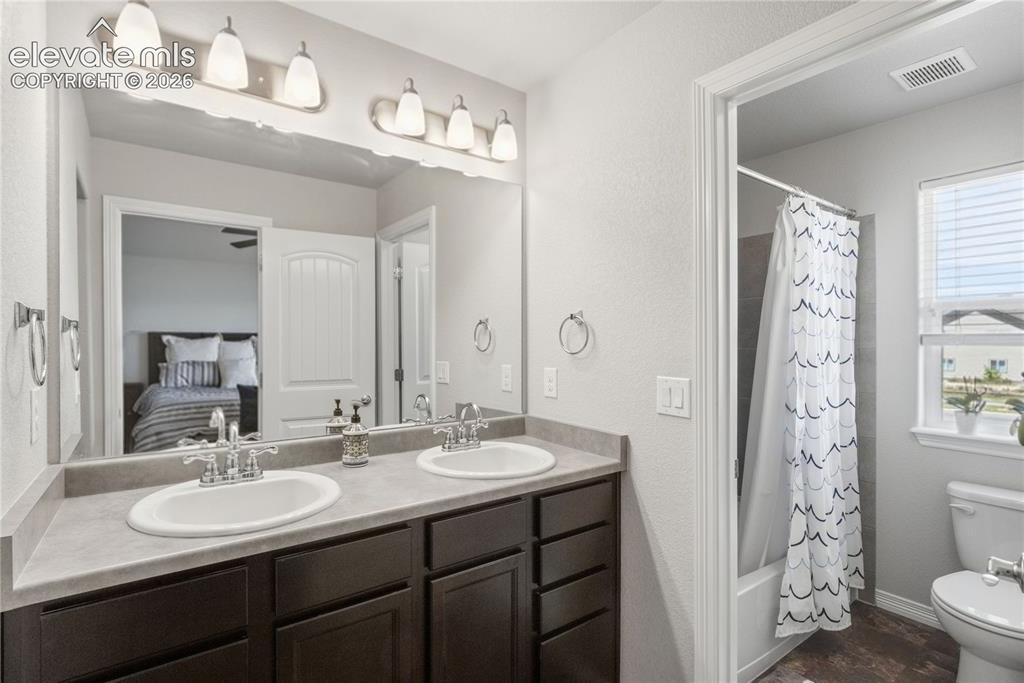 Image 29 of 50: Dual vanity with dark wood-finish cabinetry, light-toned countertop, and un