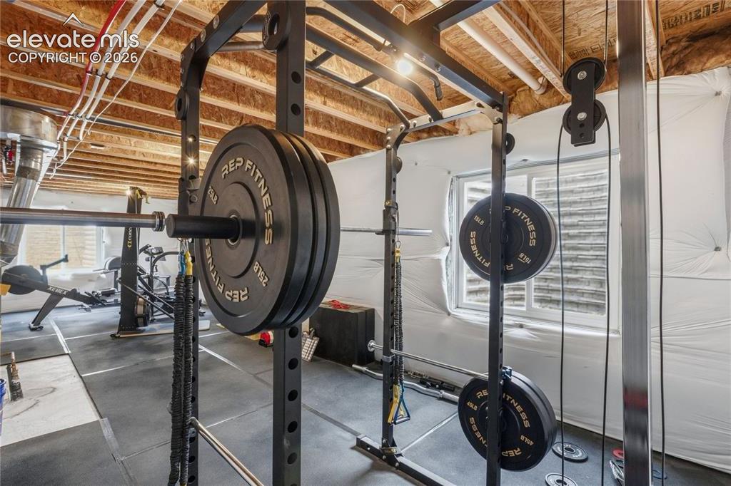 Image 33 of 50: Dedicated fitness area featuring durable rubber flooring, exposed ceiling j