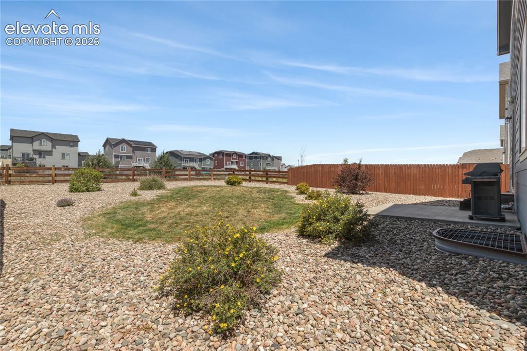 Image 34 of 50: Expansive backyard featuring a combination of rock landscaping and a centra
