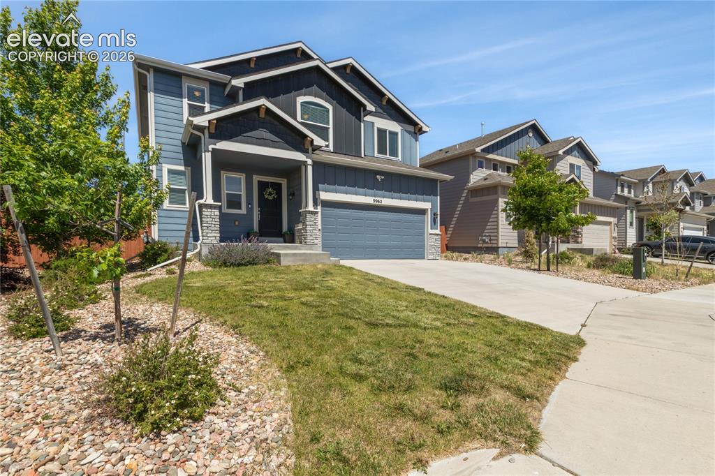 Image 4 of 50: Two-story residence featuring a two-car garage, stone accents, and a covere