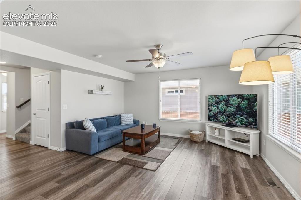 Image 7 of 50: Spacious living area featuring LVP flooring, a ceiling fan, and multiple wi