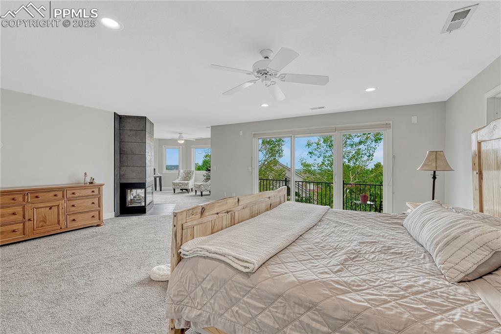 Image 10 of 47: Primary bedroom featuring access to exterior, carpet, a multi sided firepla
