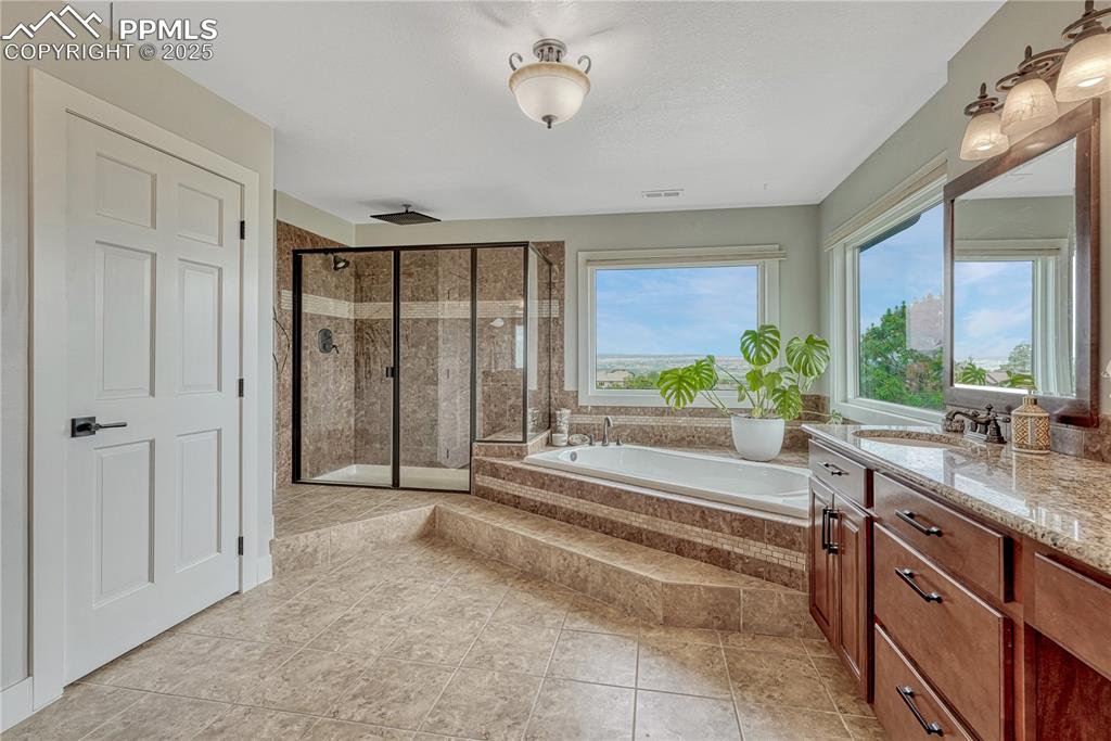 Image 12 of 47: Full primary bathroom featuring a shower stall, vanity, and a bath