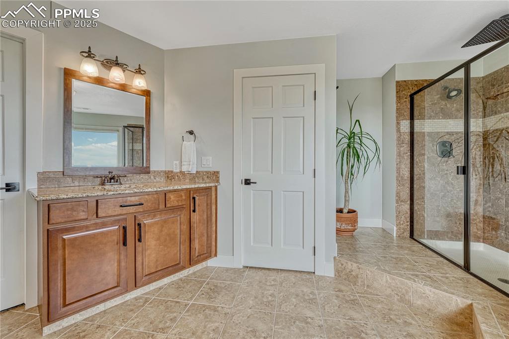 Image 13 of 47: Primary bathroom featuring 2nd  vanity, a shower stall, and tile patterned 