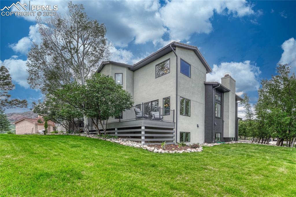 Image 16 of 47: Rear view of property featuring a yard, a chimney, stucco siding, and a dec