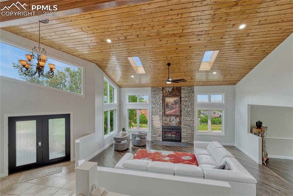 Image 19 of 47: Living room featuring wood ceiling, a skylight, a fireplace, french doors, 