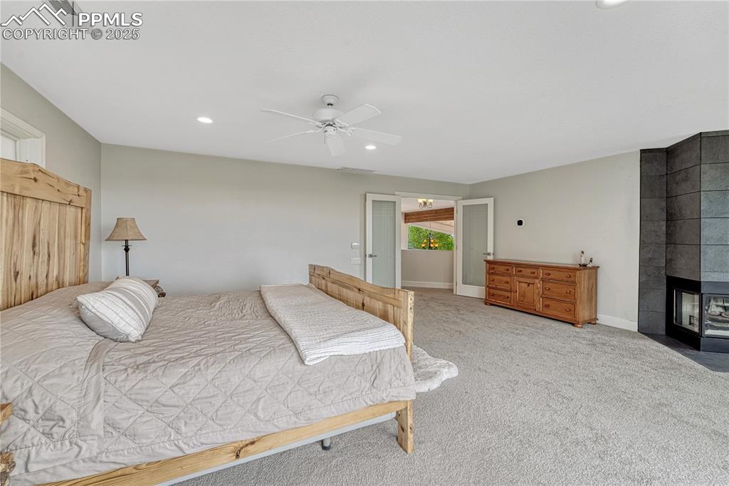 Image 20 of 47: Bedroom featuring light colored carpet, a tiled fireplace, recessed lightin