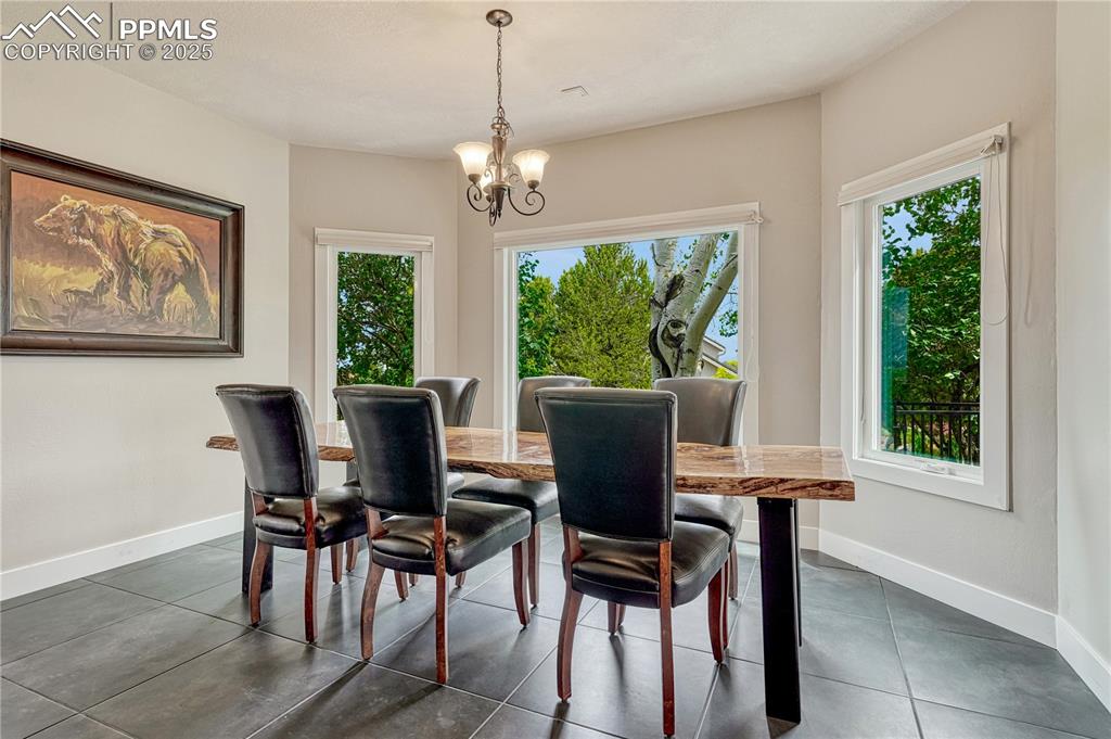 Image 26 of 47: Dining space with a chandelier and dark tile patterned flooring