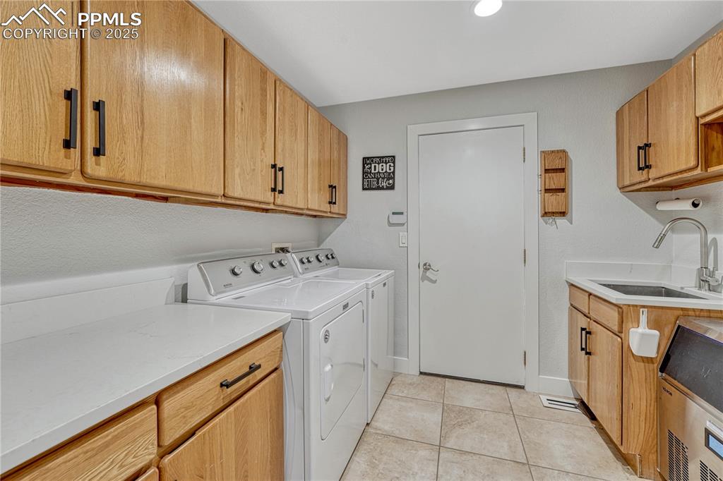Image 28 of 47: Laundry area featuring independent washer and dryer, cabinet space, and lig
