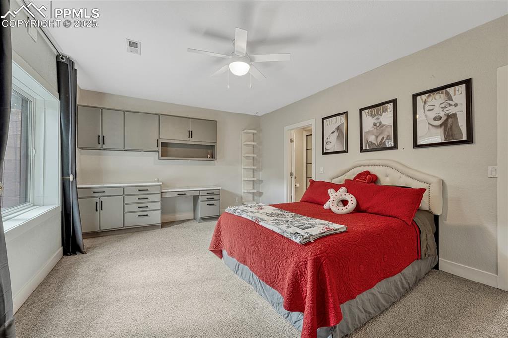 Image 30 of 47: Bedroom featuring light colored carpet, multiple windows, and a ceiling fan