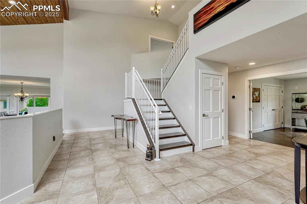 Image 32 of 47: Staircase with a chandelier, high vaulted ceiling, and recessed lighting