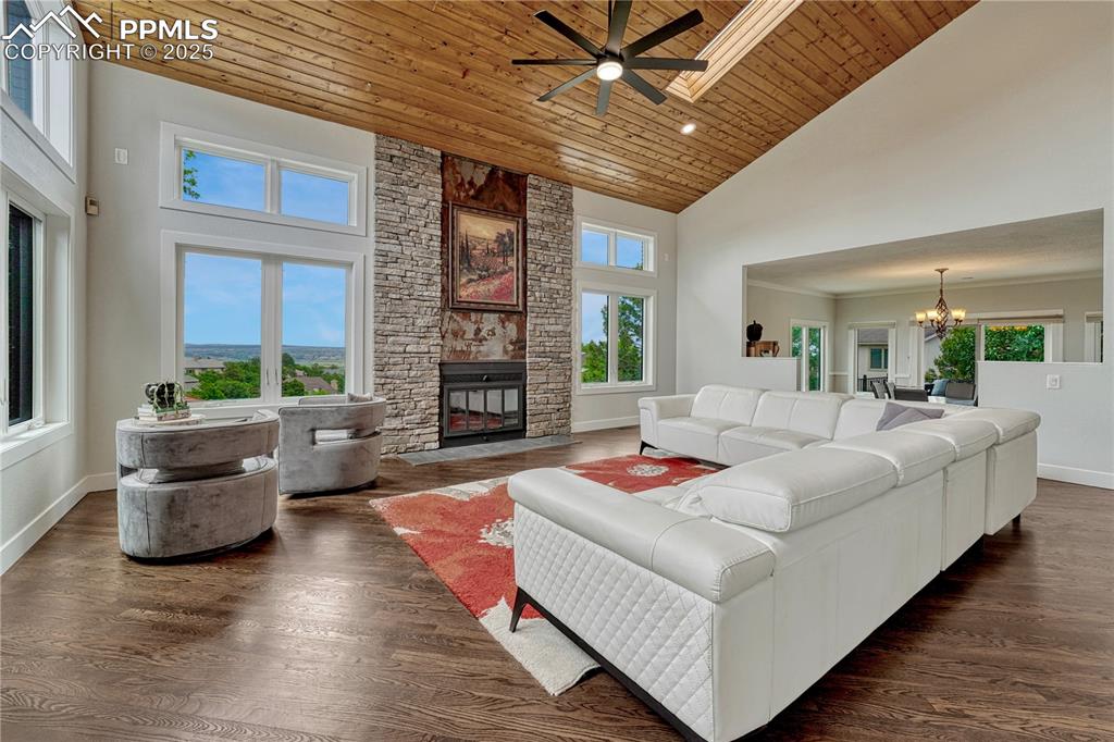 Image 33 of 47: Living area featuring high vaulted ceiling, a stone fireplace, wood ceiling