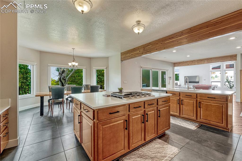 Image 35 of 47: Kitchen featuring a kitchen island, stainless steel gas stovetop, light cou