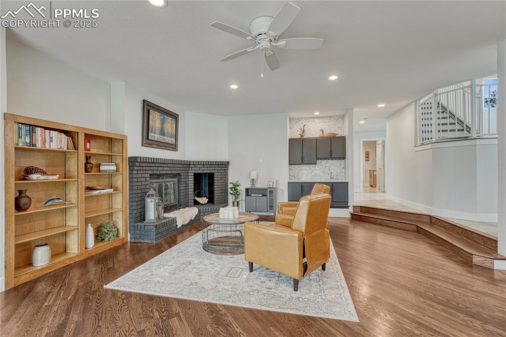Image 36 of 47: Living room with a fireplace, a ceiling fan, dark wood-style floors, and re