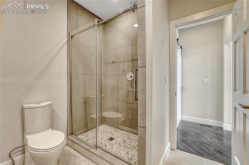 Image 41 of 47: Full bath featuring a shower stall and a textured wall