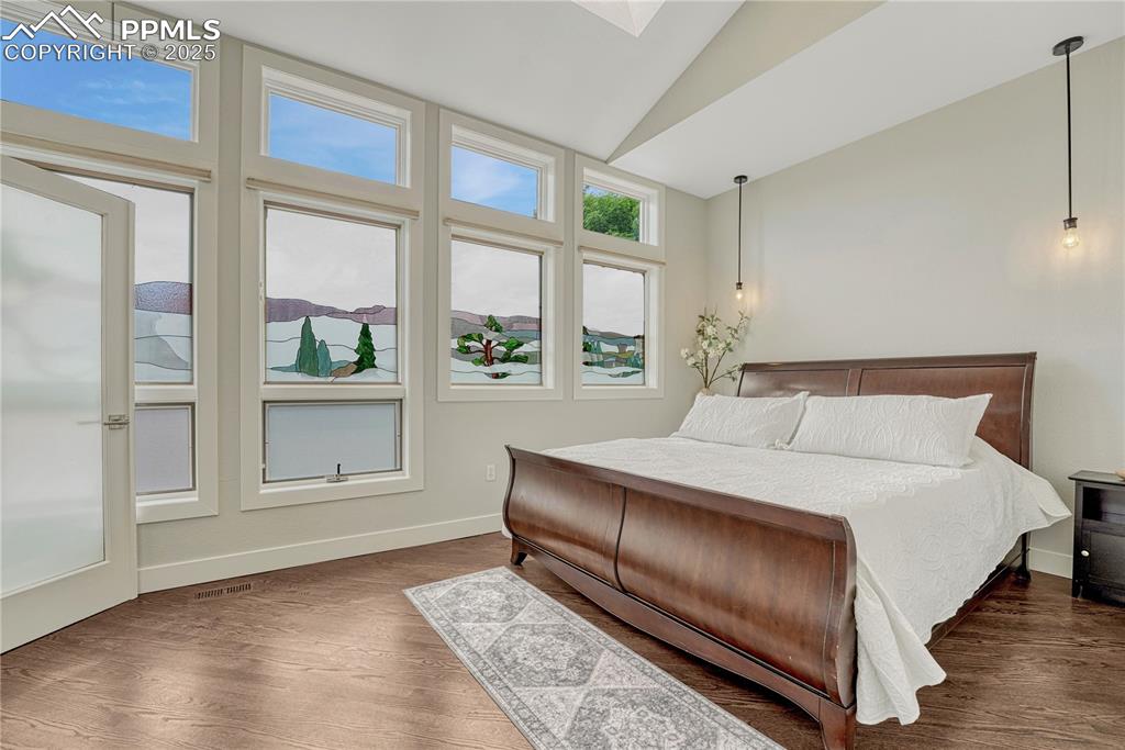 Image 42 of 47: Bedroom with lofted ceiling and dark wood-style flooring