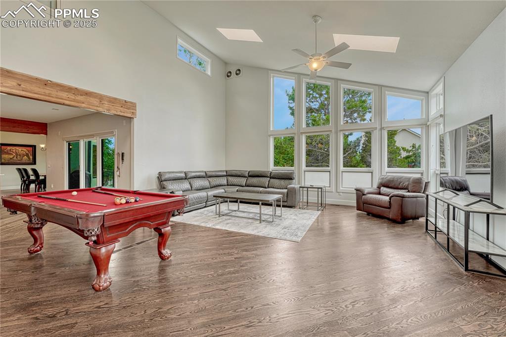 Image 44 of 47: Rec room featuring a towering ceiling, a skylight, wood finished floors, bi