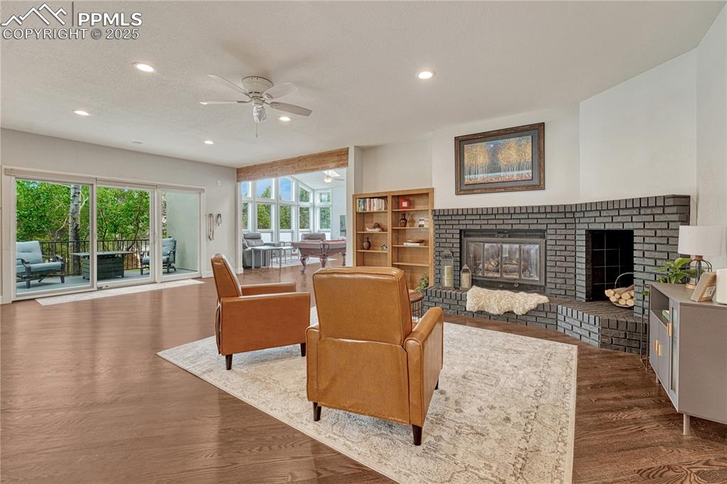 Image 46 of 47: Living room featuring a fireplace, ceiling fan, recessed lighting, and wood