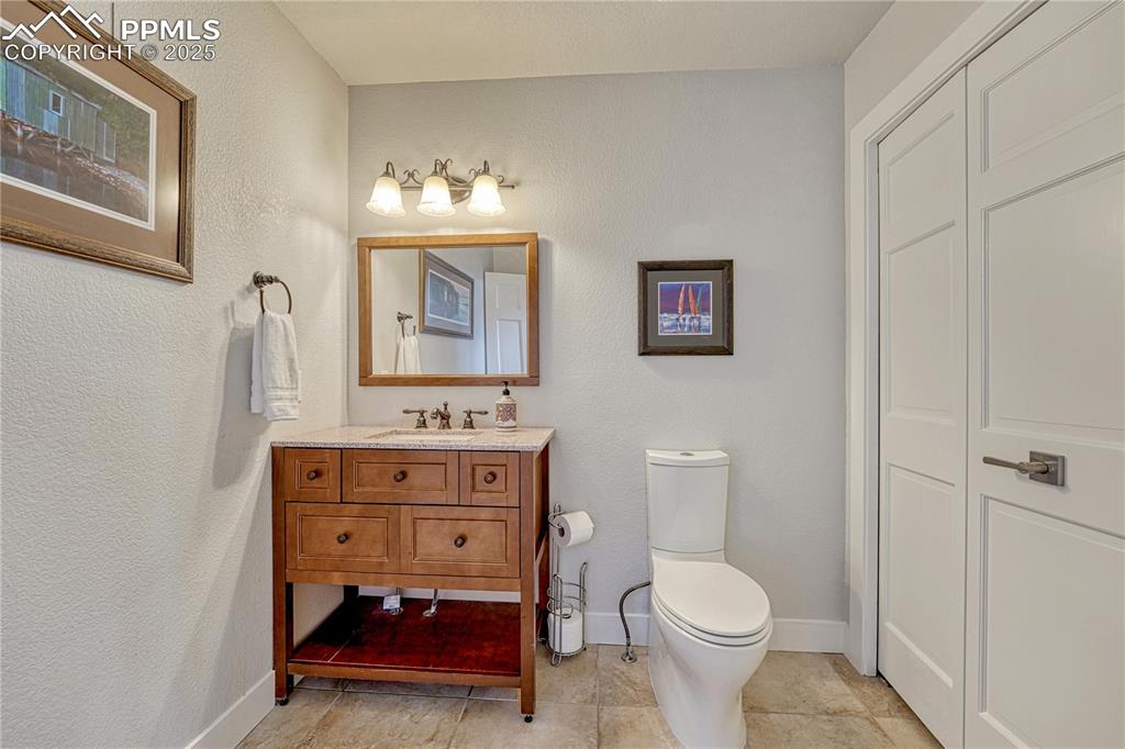 Image 8 of 47: Main level bathroom with vanity, tile patterned floors, and a textured wall
