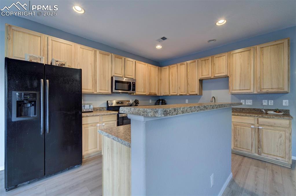 Image 24 of 43: Kitchen featuring stainless steel appliances, light brown cabinetry, recess