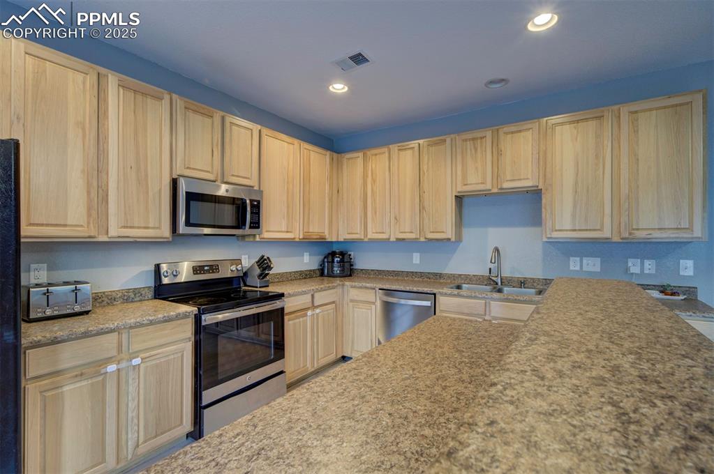 Image 25 of 43: Kitchen with stainless steel appliances, recessed lighting, light brown cab