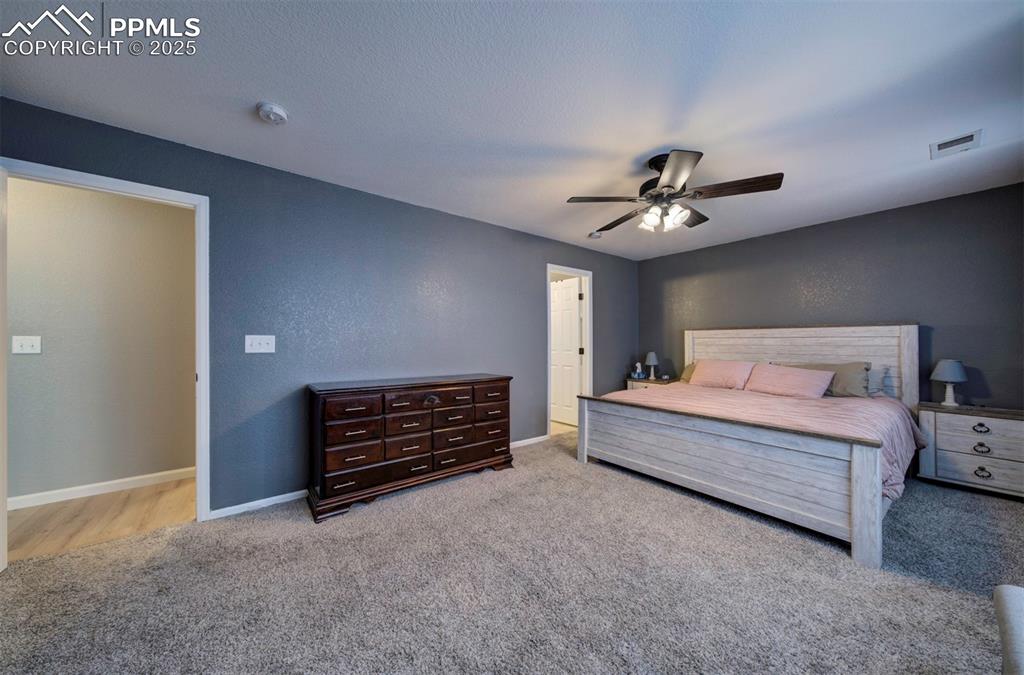 Image 29 of 43: Bedroom featuring a textured wall, a ceiling fan, light carpet, and a textu