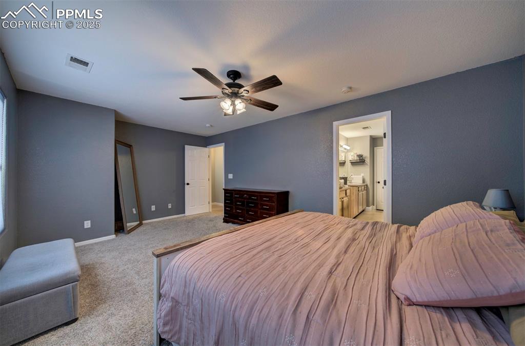Image 30 of 43: Bedroom featuring ceiling fan, light colored carpet, and ensuite bath