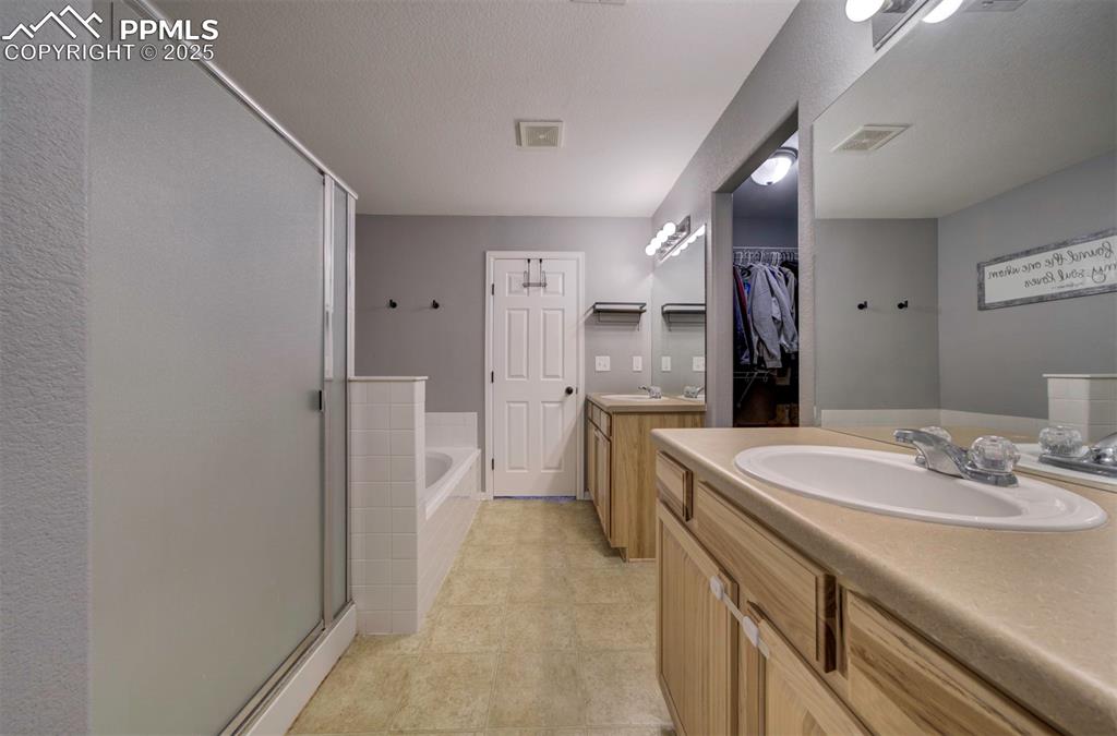 Image 36 of 43: Full bathroom with two vanities, a bath, a shower stall, a spacious closet,