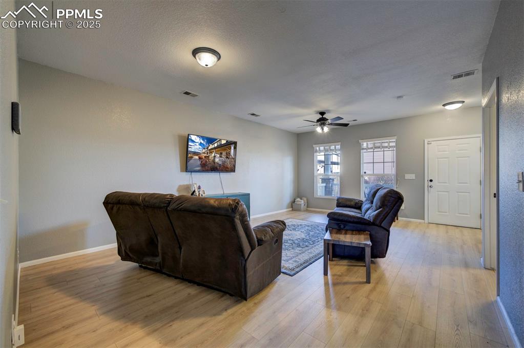 Image 6 of 43: Living room featuring light wood-style floors, ceiling fan, and a textured 