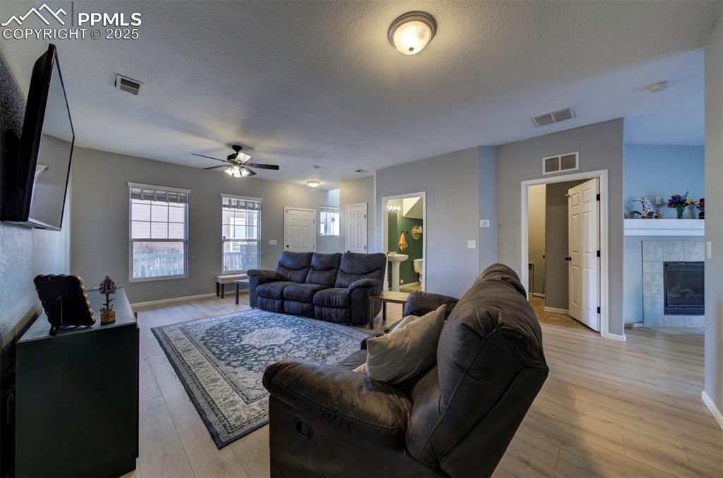 Image 7 of 43: Living area with a tile fireplace, a textured ceiling, light wood finished 