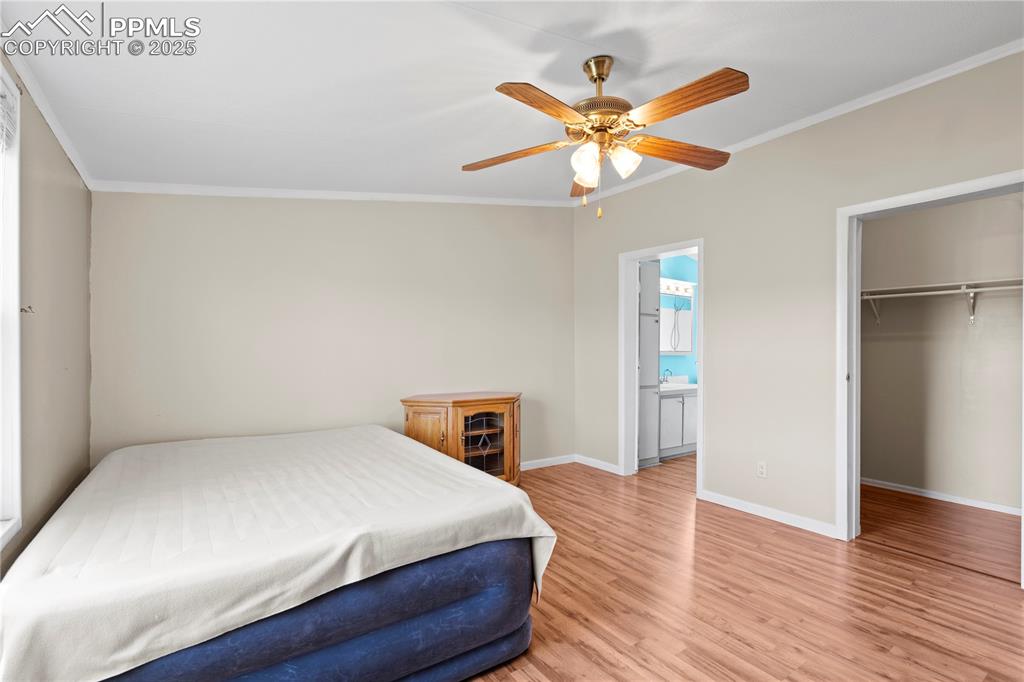Image 13 of 29: Bedroom with ornamental molding, wood finished floors, a spacious closet, a