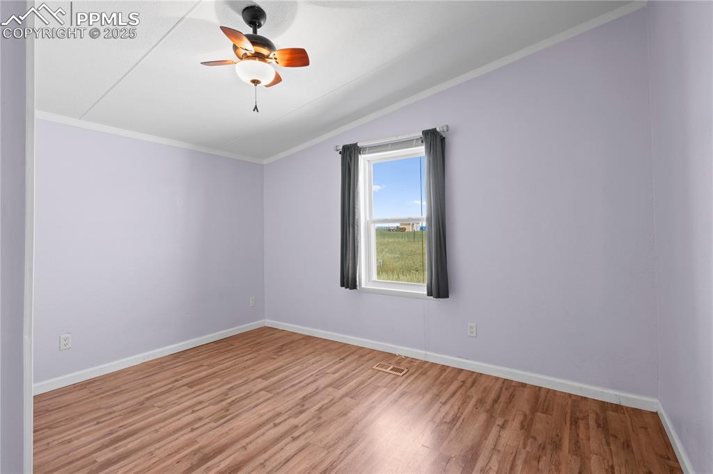 Image 17 of 29: Empty room featuring wood finished floors, lofted ceiling, ornamental moldi