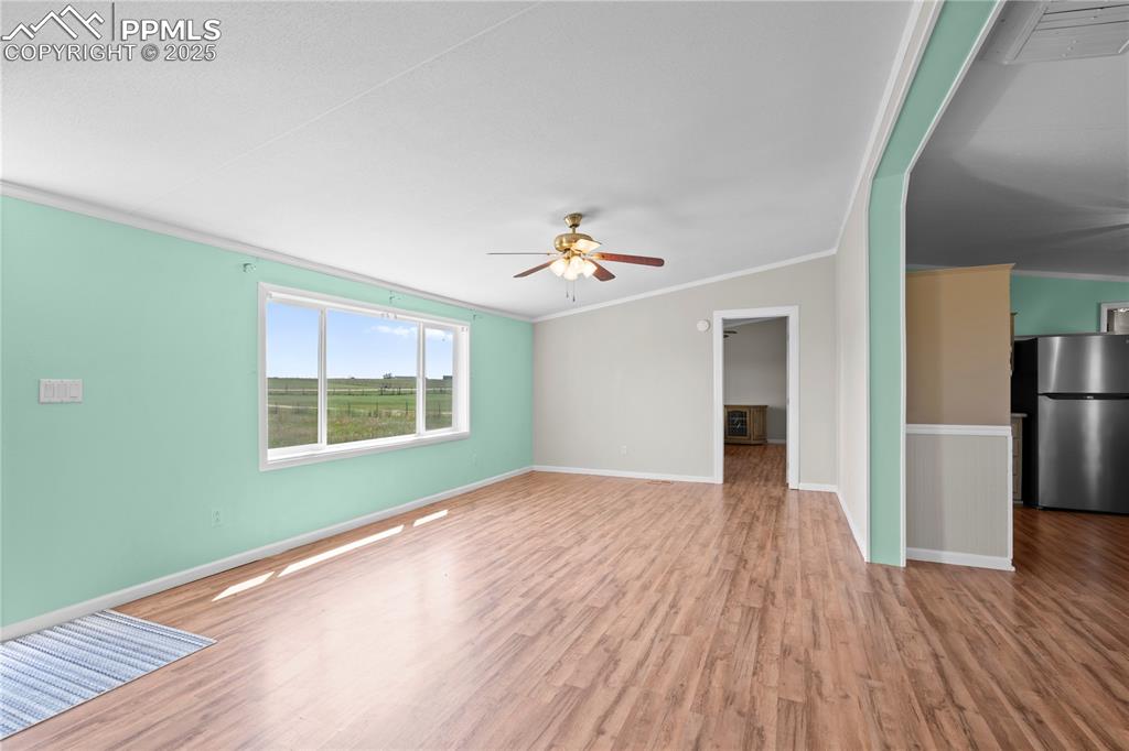Image 4 of 29: Unfurnished living room with crown molding, wood finished floors, and a cei